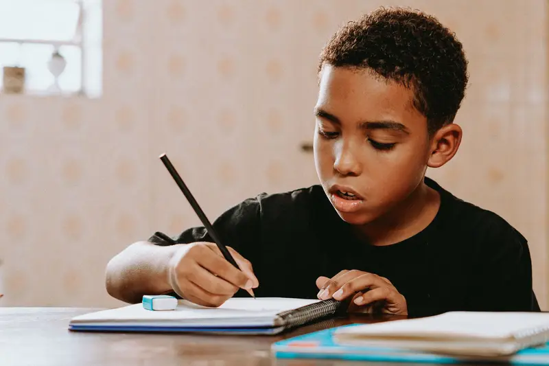 A student writing in a notebook at a table